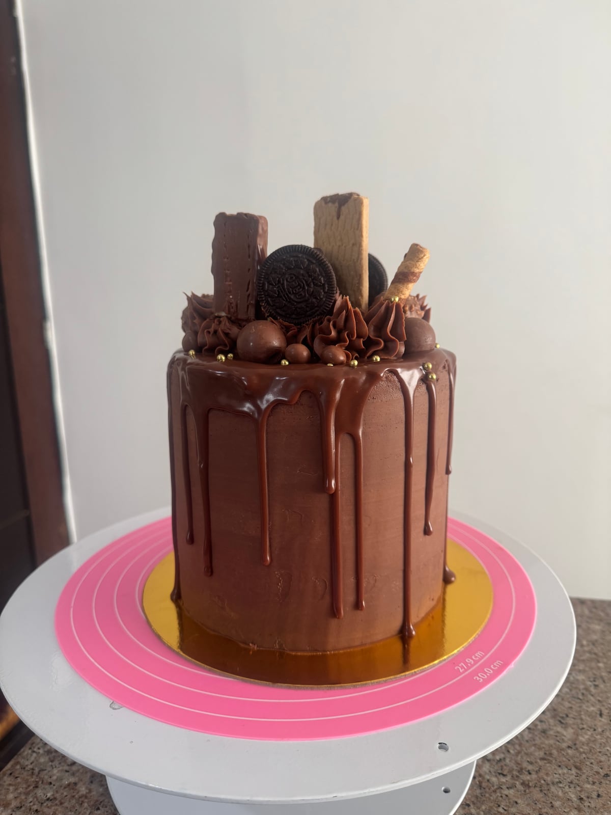 Torta marrón con goteo, galletas y barras decorativas en la parte superior.