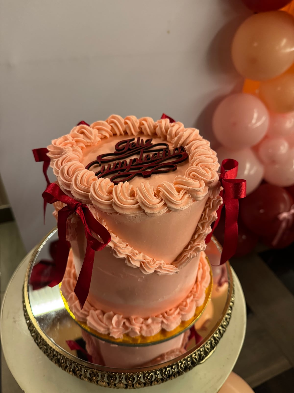 Torta rosa con ondas de manga y lazos burdeos.